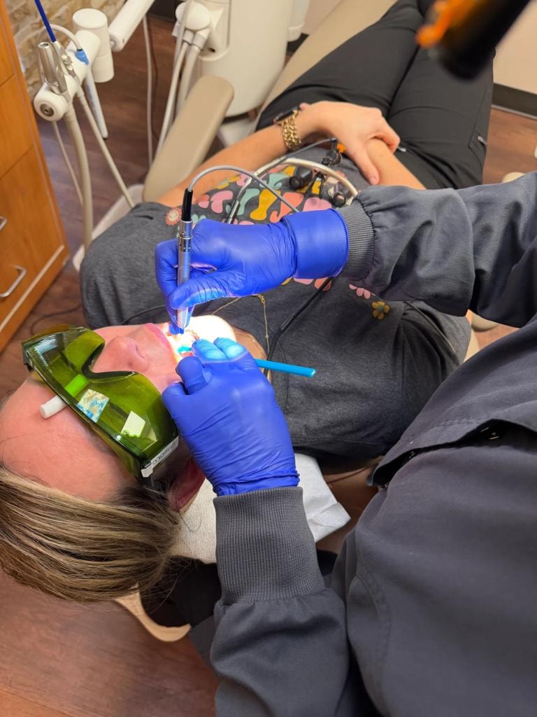 Dental professional performing hands-on laser procedure during certification training